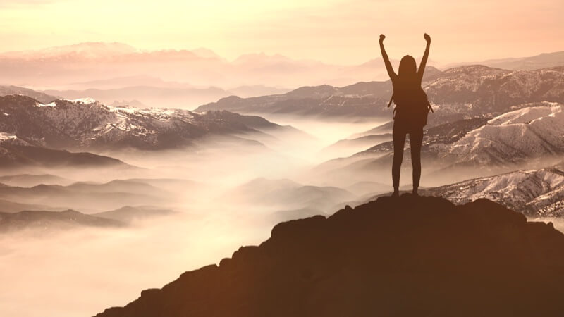 Woman with raised arms on mountain top